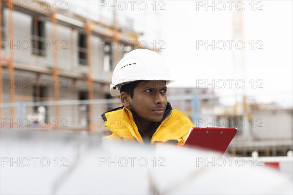 Young technician with helmet and yellow protective jacket working outside