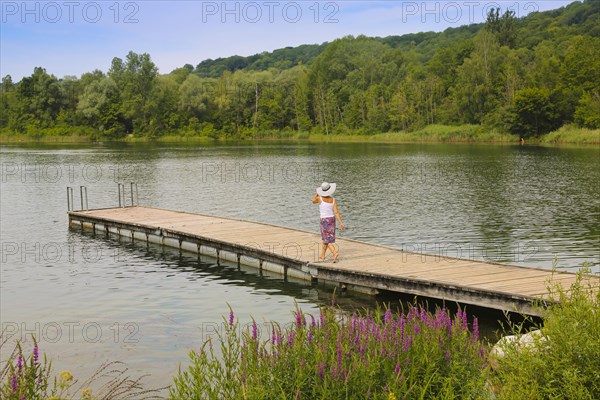 Woman in sun hat and skirt walking on jetty