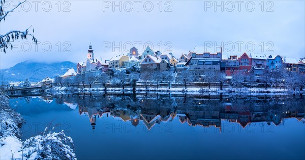 Christmas illuminated house facade of Frohnleiten reflected in the river Mur