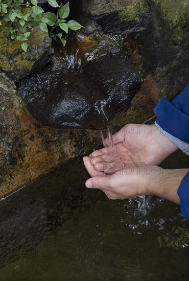 Hiker washing his hands at the fountain to the path to Rocha da Relva