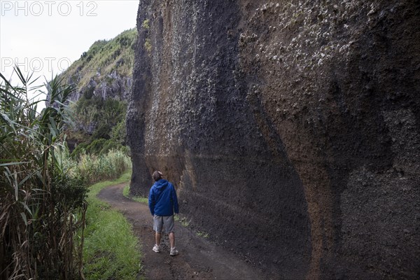 Hikers on the path to Rocha da Relva past eroded lava rocks