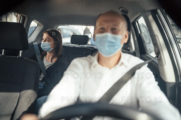 Taxi driver in a mask with a female client on the back seat wearing mask