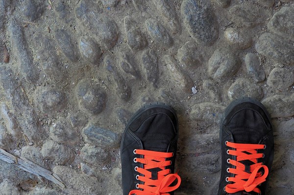 Black sports shoes with red shoe laces on street