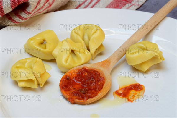 Pasta and cooking spoon with tomato sauce on plate