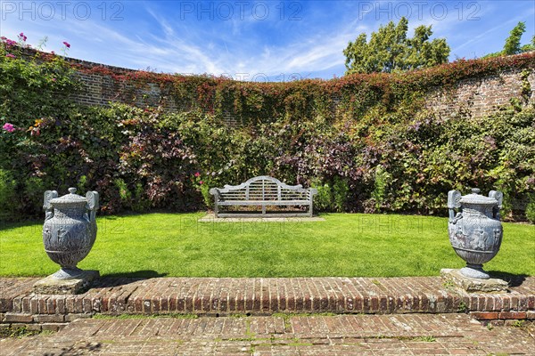 Garden bench with two amphorae in a cottage garden