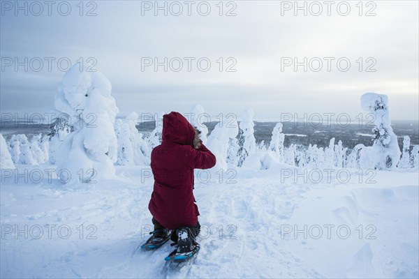 Photographer taking pictures of snow-covered trees