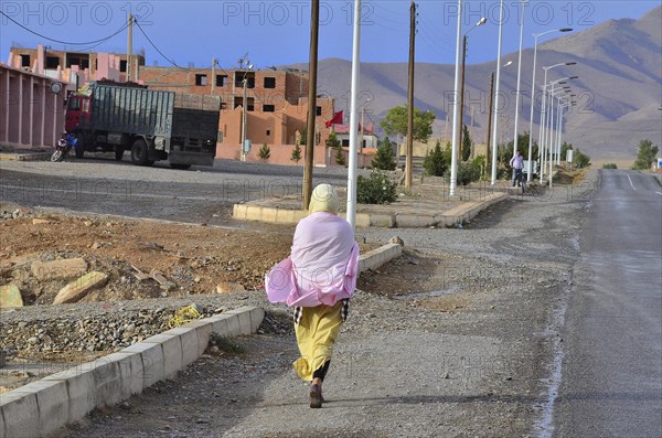 Woman walking on pavement in front of new housing estate under construction