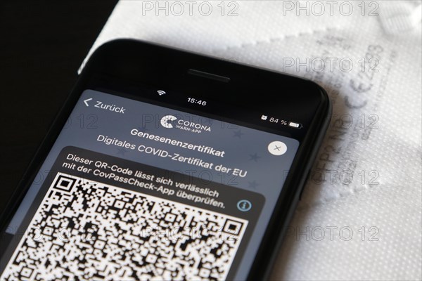 FFP2 mask and iPhone with Corona warning app with QR code for certificate of recovery