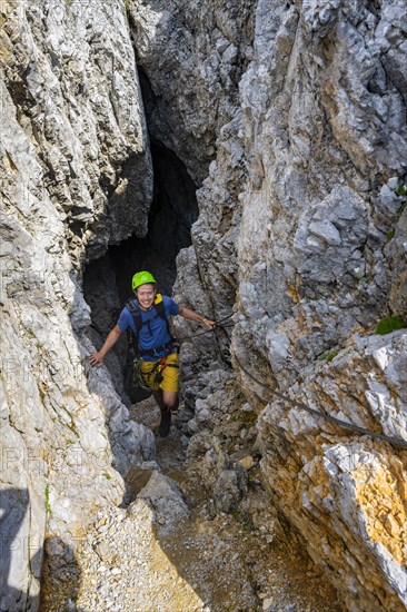 Young man climbing out of a rock hole