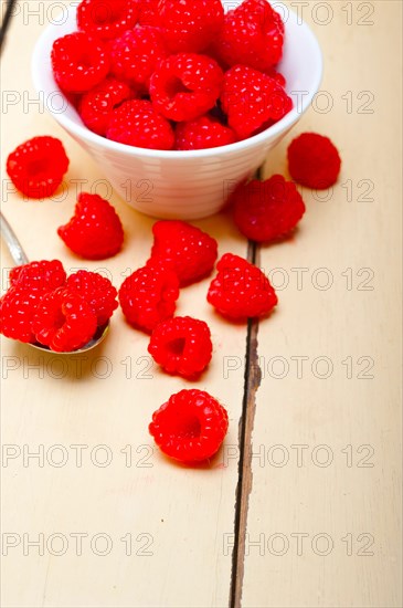 Bunch of fresh raspberry on a bowl and white wood rustic table