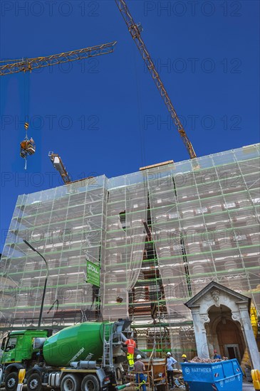 Construction worker with concrete pouring funnel on crane