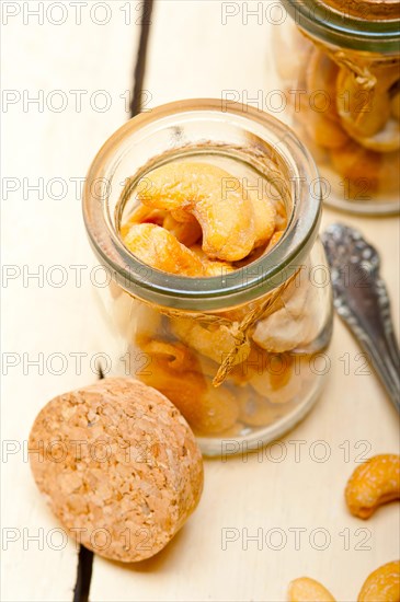 Cashew nuts on a glass jar over white rustic wood table