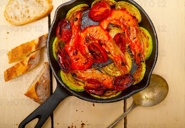 Roasted shrimps on cast iron skillet with zucchini and tomatoes