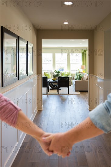 Couple holding his hands and walking through hallway of a new house