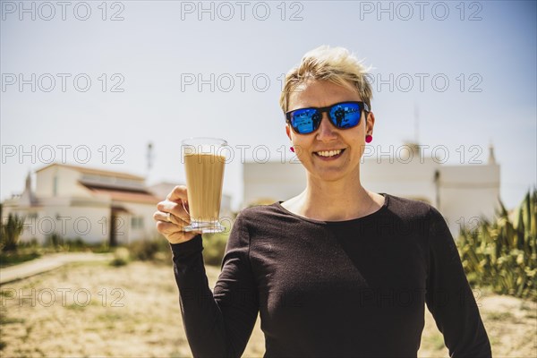 Happy woman with big coffee with milk during vacations in Portugal