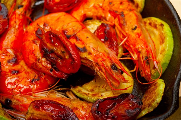 Roasted shrimps on cast iron skillet with zucchini and tomatoes