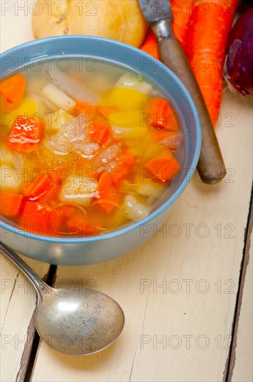 Traditional Italian minestrone soup on a rustic table with ingredients