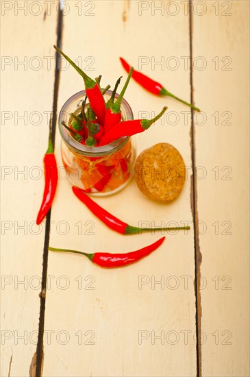 Red chili peppers on a glass jar over white wood rustic table