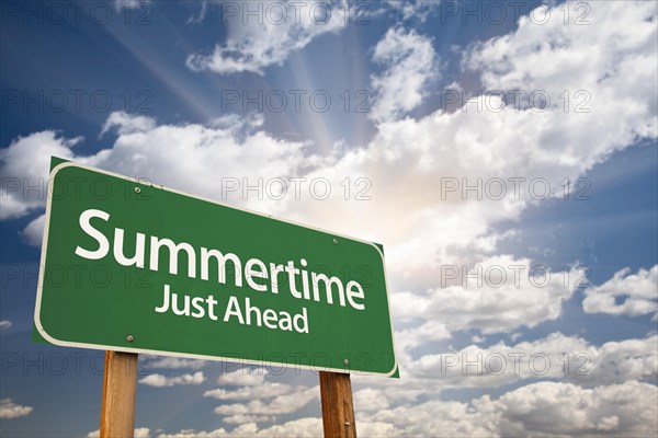 Summertime green road sign with dramatic clouds