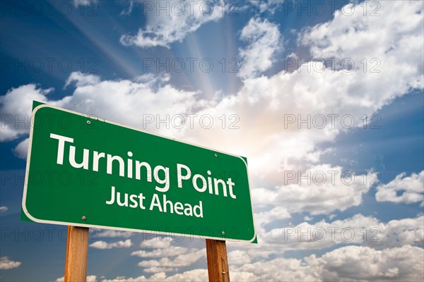 Turning point green road sign with dramatic clouds