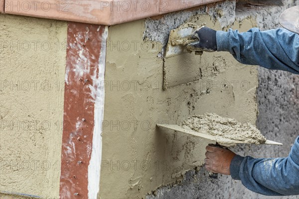 Tile worker applying cement with trowel at pool construction site