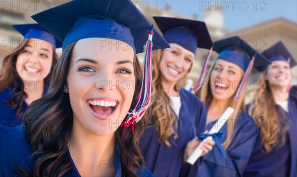 Happy graduating group of girls in cap and gown celebrating on campus