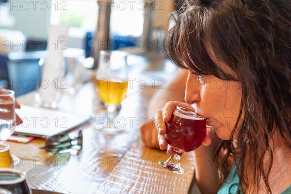 Female sipping glass of micro brew beer at bar with friends