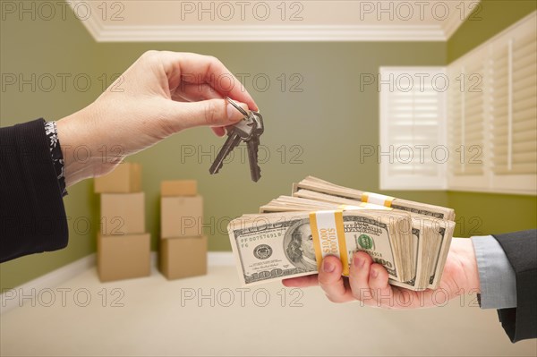 Man and woman handing over cash for house keys inside empty green room with boxes