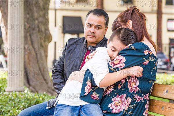 Caucasian mother and hispanic father comforting mixed-race son outdoors