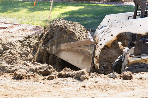 Small bulldozer digging in yard for pool installation