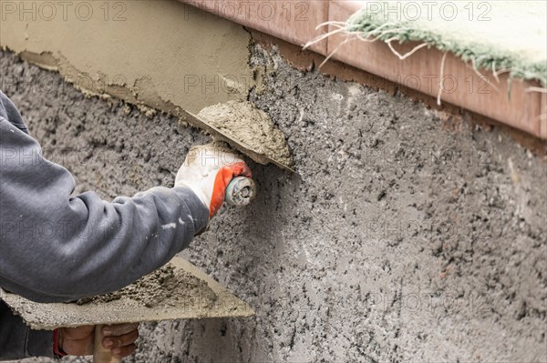 Tile worker applying cement with trowel at pool construction site