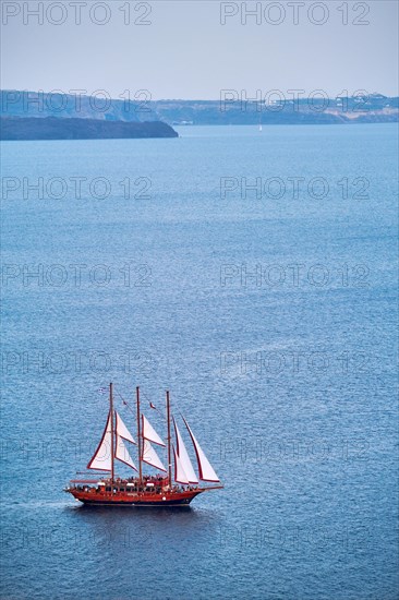 Tourist schooner vessel ship boat in Aegean sea near Santorini island with tourists going to sunset viewpoint. Santorini