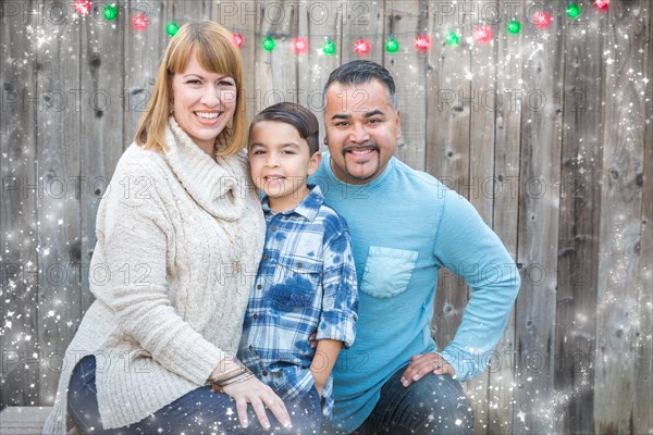 Happy young mixed-race family portrait outside with christmas lights and snow effect