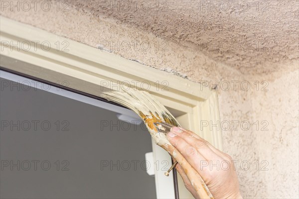 Professional painter cutting in with A brush to paint house door frame