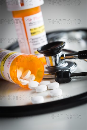 Non-Proprietary medicine prescription bottles and spilled pills abstract with stethoscope