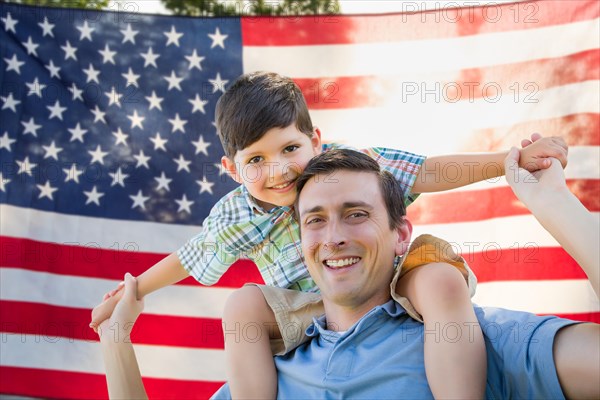 Father with son piggy back riding in front of american flag