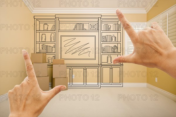Hands framing drawing of entertainment unit in empty room with moving boxes