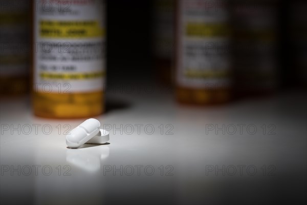 Hydrocodone pills and prescription bottles under spot light