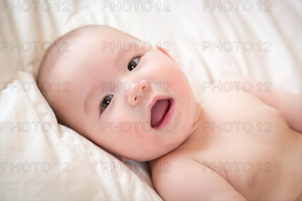 Young mixed-race chinese and caucasian baby boy having fun on his blanket