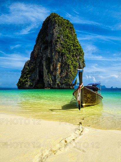 Long tail boat on tropical beach with limestone rock