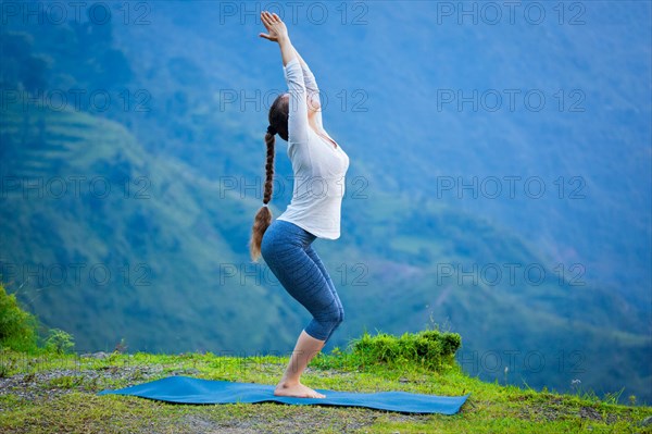 Young sporty fit woman doing yoga asana Utkatasana