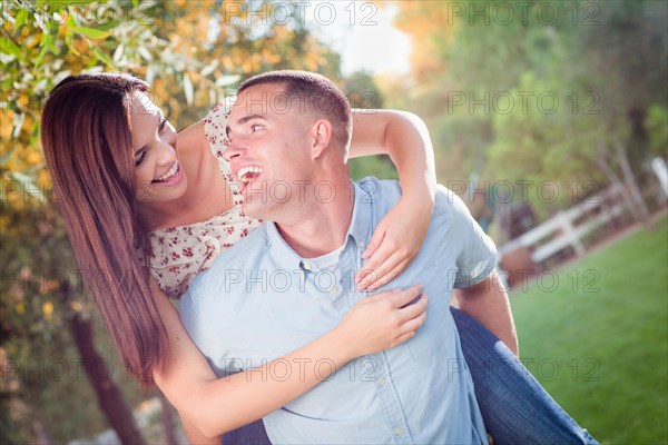 Happy romantic caucasian couple piggyback riding in the park