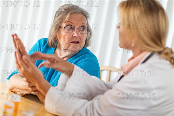 Female doctor talking with senior adult woman about hand therapy