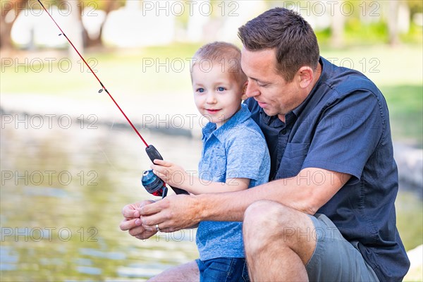 Young caucasian father and son having fun fishing at the lake