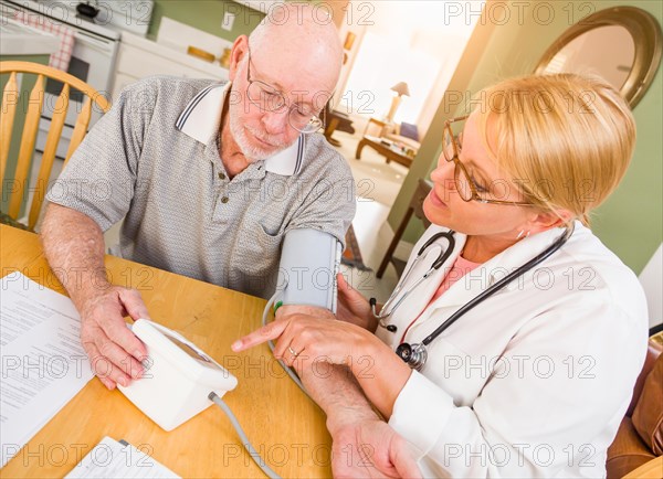 Female nurse or doctor helping senior adult man take blood pressure in home