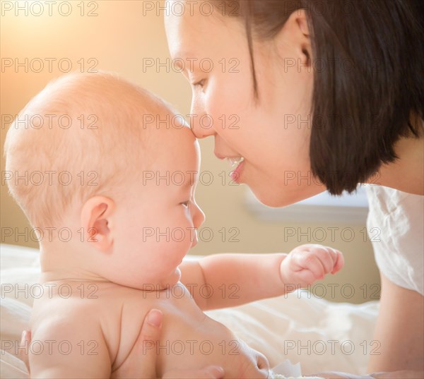 Young mixed-race chinese and caucasian baby boy laying in his bed with his mother