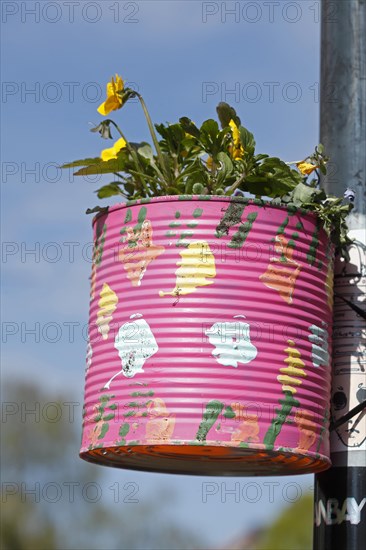 Colourfully painted tin can as a flower pot