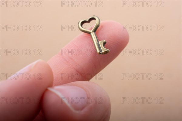 Tiny key with heart shape placed on the finger tip