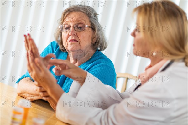 Female doctor talking with senior adult woman about hand therapy