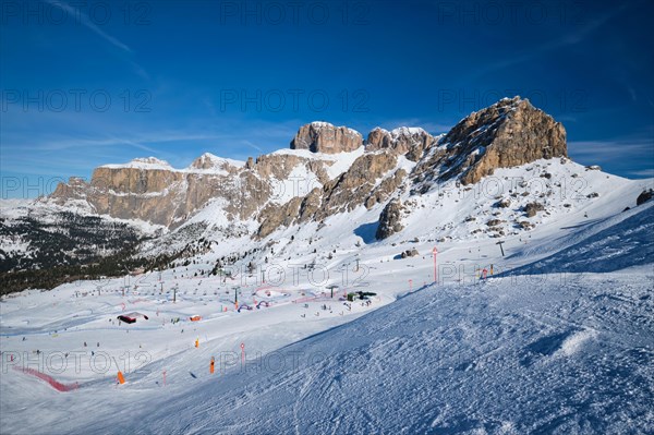 View of a ski resort piste with people skiing in Dolomites in Italy